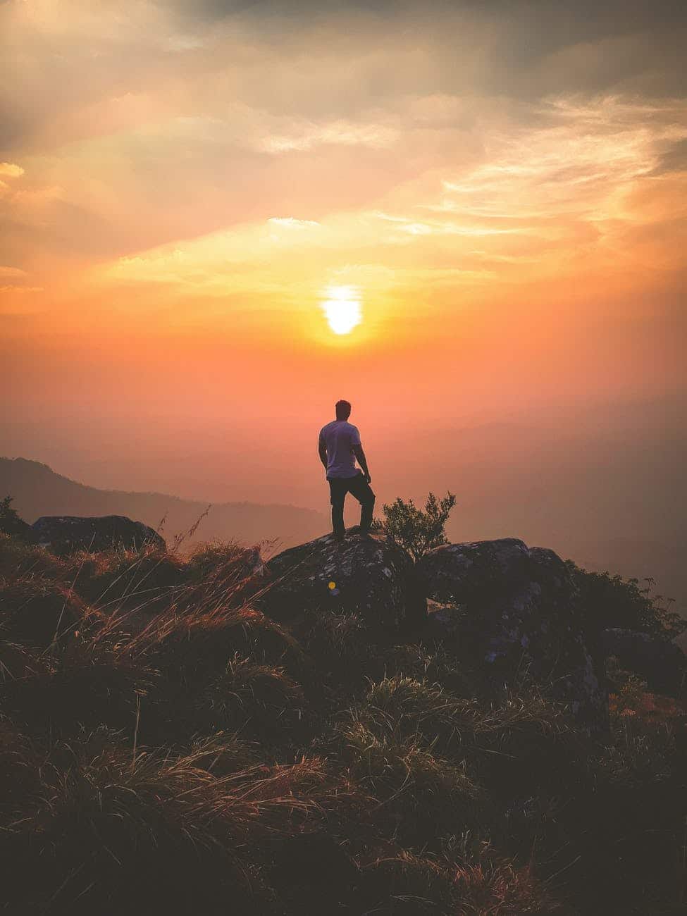 man standing on rock during sunset