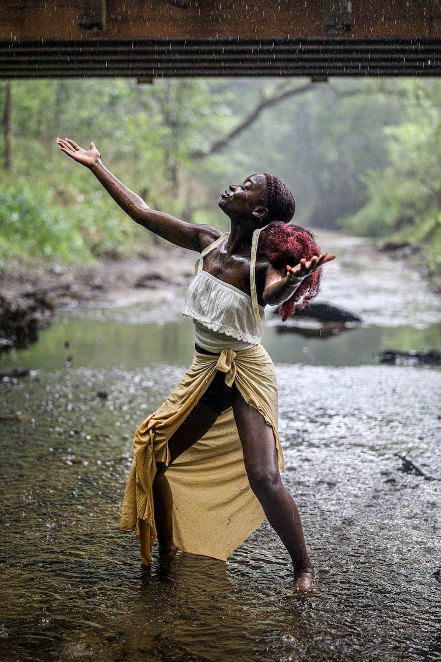 woman enjoying the rain while standing on a shallow river